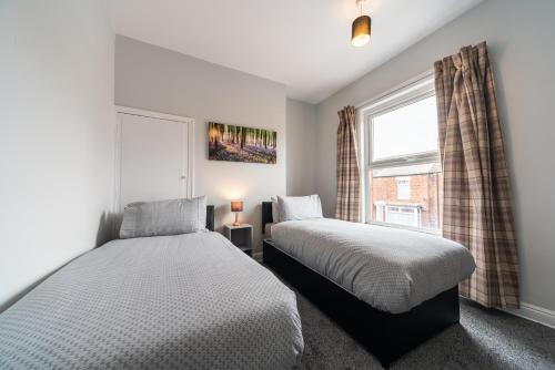 2 Betten in einem Schlafzimmer mit Fenster in der Unterkunft 3 Bedroom Hull Sleeps 6 Glam Contractor & Leisure & Families in Hull