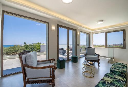 a living room with a couch and chairs and windows at Incognito Creta Luxury Suites and More in Kolymvari