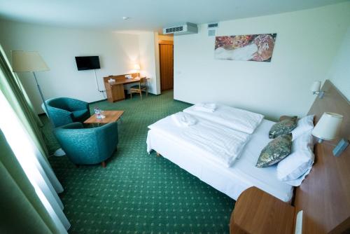 a hotel room with a bed and a chair at Hotel Tigra in Priekuļi