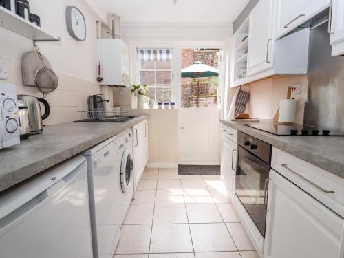 a white kitchen with white cabinets and appliances at Tower View Cottage in Chester