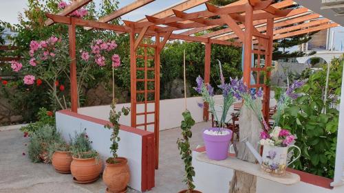 a wooden pergola with a bunch of flowers in pots at Irene Studios in Kefalos