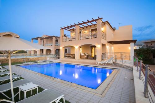 a villa with a swimming pool in front of a house at Irida Villa in Rethymno Town