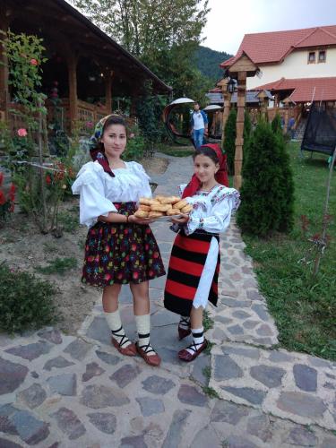 two young girls holding a basket of carrots at Pensiunea Valea Branzei in Năneşti