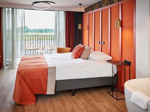 - une chambre avec un grand lit et un balcon dans l'établissement De Maasparel Nextdoor Suites, à Arcen