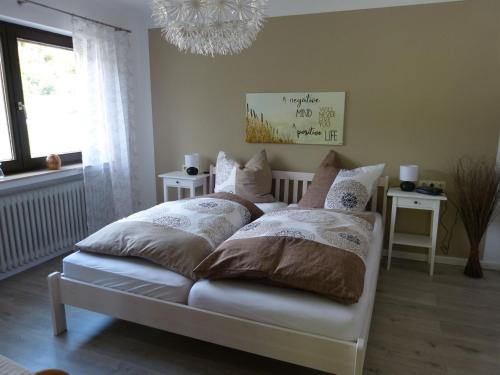 sypialnia z łóżkiem z poduszkami i żyrandolem w obiekcie Ferienwohnung Haus Wiesengrund w mieście Forbach