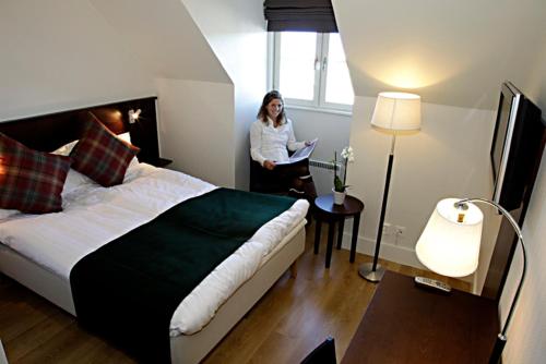 a woman standing in a hotel room with a bed at Rasta Kalmar in Kalmar
