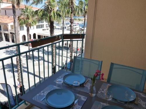 une table avec des plaques bleues sur un balcon avec des palmiers dans l'établissement Le nid de la Mouette, à Argelès-sur-Mer