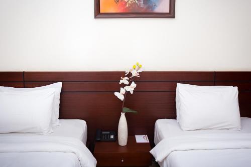 a hotel room with two beds and a vase with flowers at Hotel du Golfe in Lomé