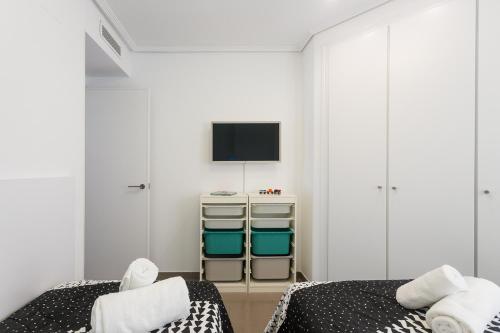 a bedroom with two beds and a tv on the wall at ApartUP Patacona Essence in Valencia