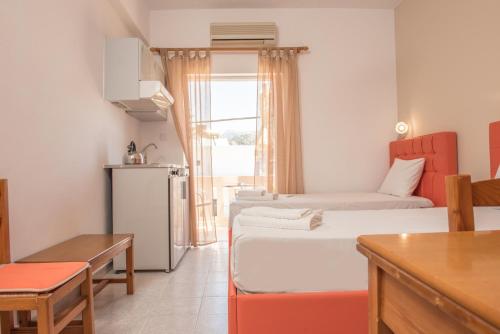 a small room with two beds and a kitchen at Nikos Rooms in Palaiochora