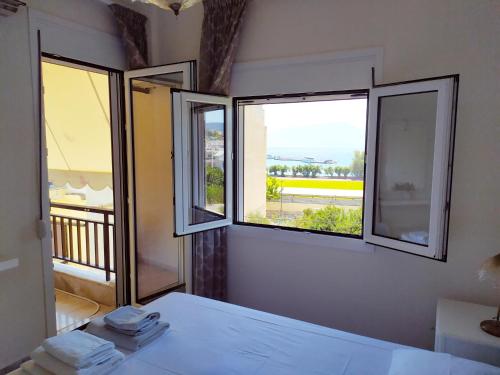 1 Schlafzimmer mit 2 Fenstern und 1 Bett mit Handtüchern in der Unterkunft Amazing Apartment next to the sea! in Agios Nikolaos