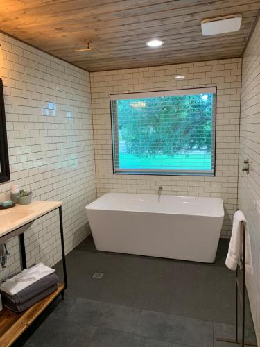 baño con bañera blanca y ventana en Salado Cottage Retreat near Downtown, en Salado