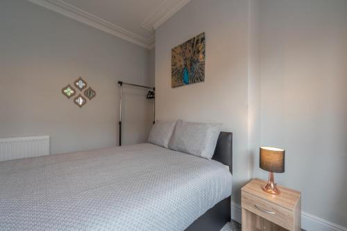 a bedroom with a bed and a lamp on a night stand at 3 Bedroom Hull Sleeps 6 Glam Contractor & Leisure & Families Close to Clough Rd in Hull