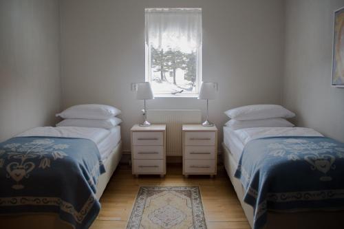two twin beds in a room with a window at Hotel Siglunes in Siglufjörður