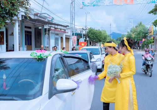dos mujeres están de pie junto a un coche blanco en Khách Sạn Sơn Hạ, en Kon Tum