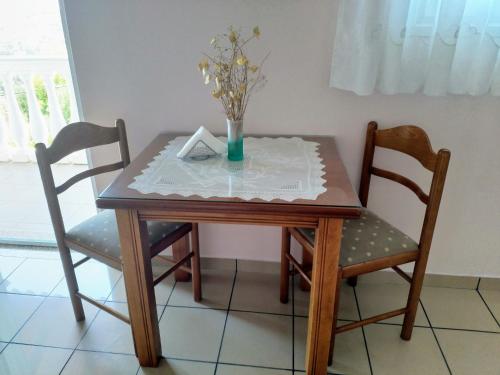 科孚城的住宿－spiros maria studios，一张桌子,两把椅子,花瓶上放着鲜花