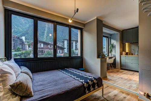 sypialnia z łóżkiem i dużymi oknami w obiekcie Chamonix City Center Luxury Studio Apartment w Chamonix-Mont-Blanc