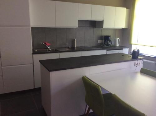 a kitchen with white cabinets and a table and chairs at Ter Ename 3 in Oudenaarde
