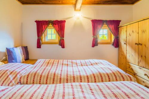 a bedroom with two beds and two windows at Almhütte Brandgut in Mühlbach am Hochkönig