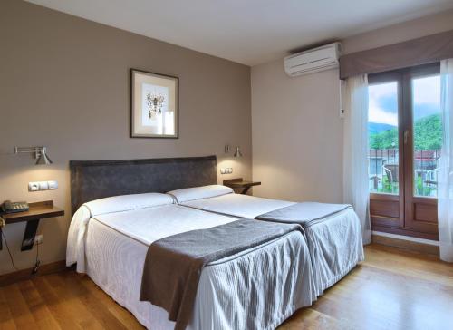 a bedroom with a large white bed and a window at Hotel Rural Izar Ondo in Arbizu
