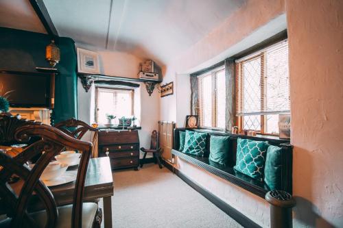 uma sala de estar com um sofá verde e janelas em The Rookery Nook and Brontë Parsonage - Haworth em Haworth