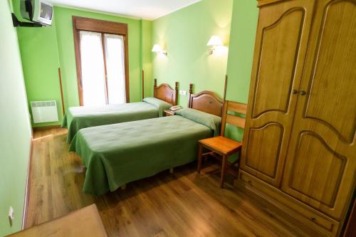 a green room with two beds and a couch at Pension Monteverde in Cangas de Onís