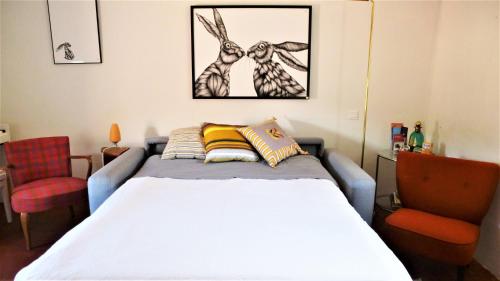um quarto com uma cama branca e uma cadeira vermelha em La Cachette village em Roussillon
