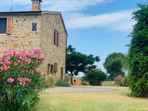 an old stone building with pink flowers in front of it at Tenuta di Montemassi Podere Raspollino in Montemassi