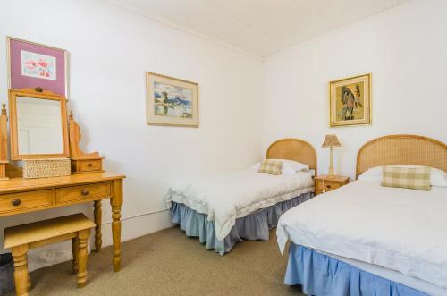 a bedroom with two beds and a dresser and a mirror at Natte Valleij in Klapmuts
