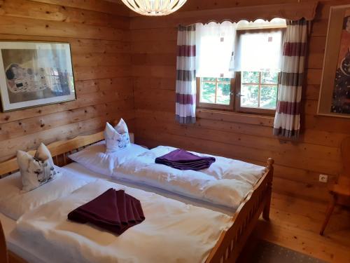 Villa Weitblick في فالدمونشن: سريرين في غرفة بجدران خشبية ونوافذ