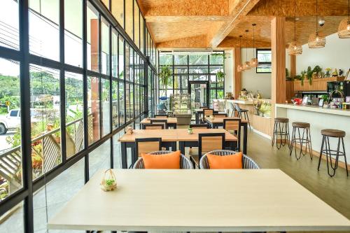 a restaurant with tables and chairs and large windows at Dee Homestay in Ban Pa Khlok