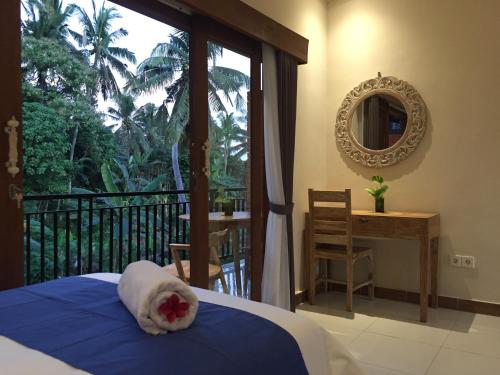 a bedroom with a bed and a balcony with a mirror at Cahaya Guest House in Ubud