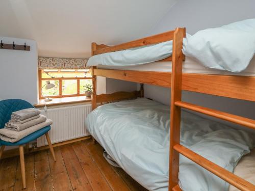 een slaapkamer met 2 stapelbedden en een stoel bij Preacher's Cottage in Llanbadarn-fynydd
