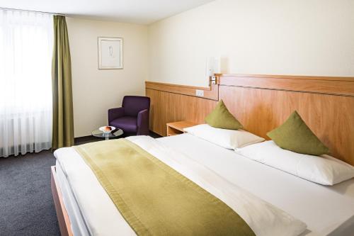 a hotel room with a large bed and a purple chair at Hotel Buchserhof in Buchs