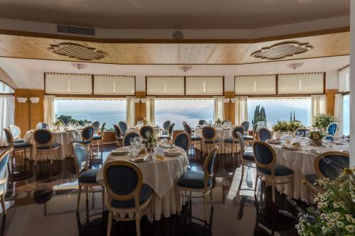 un salón de banquetes con mesas, sillas y ventanas en Hotel Laguna, en San Zeno di Montagna