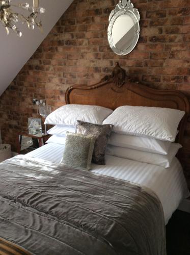 a bedroom with a large bed with a brick wall at Holly Tree Cottage in High Etherley