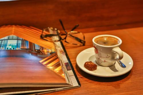 a cup of coffee on a plate next to a book at Radisson Blu São Paulo in Sao Paulo
