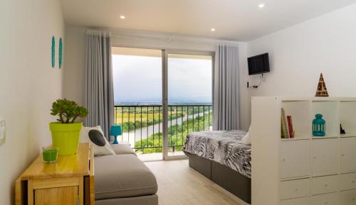 a bedroom with a bed and a couch and a balcony at Les couchers de soleil à Empuriabrava in Empuriabrava