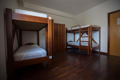 two bunk beds in a room with wooden floors at HI Vila Nova de Foz Coa - Pousada de Juventude in Vila Nova de Foz Coa