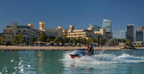 a person riding a motor bike on top of a body of water at Grand Hyatt Doha Hotel & Villas in Doha
