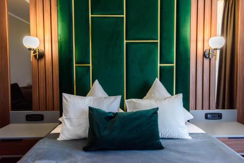 a bed with four pillows and a green wall at Vila Time Olimp in Olimp