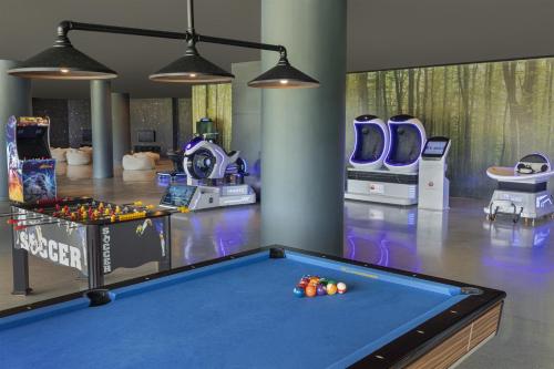 a room with a pool table and arcade games at Alma Resort Cam Ranh in Cam Ranh