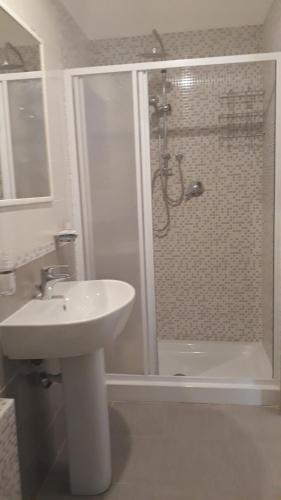 uma casa de banho branca com um chuveiro e um lavatório. em Casa Elena em Palinuro
