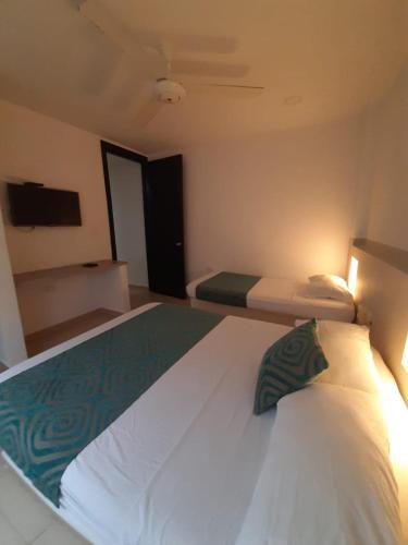 a bedroom with a large white bed with a green pillow at Apartahotel y Hotel Sofichic Boutique in Barranquilla