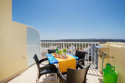 a balcony with a table and chairs and the ocean at Summer Breeze Apartment with panoramic terrace - by Getawaysmalta in Mellieħa