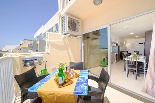 a dining room with a table and chairs on a balcony at Summer Breeze Apartment with panoramic terrace - by Getawaysmalta in Mellieħa