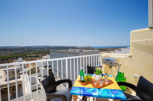 a balcony with a table and chairs on a building at Summer Breeze Apartment with panoramic terrace - by Getawaysmalta in Mellieħa