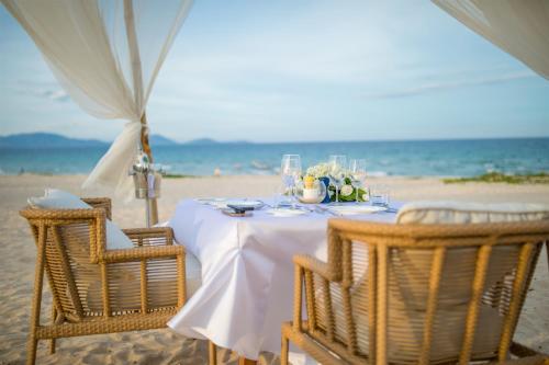 a table on the beach with a white table cloth at Alma Resort Cam Ranh in Cam Ranh