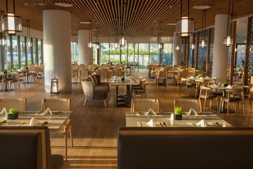a dining room with tables and chairs and windows at Alma Resort Cam Ranh in Cam Ranh