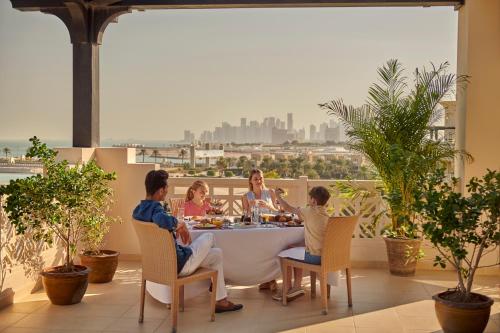 a group of people sitting around a table on a balcony at Grand Hyatt Doha Hotel & Villas in Doha